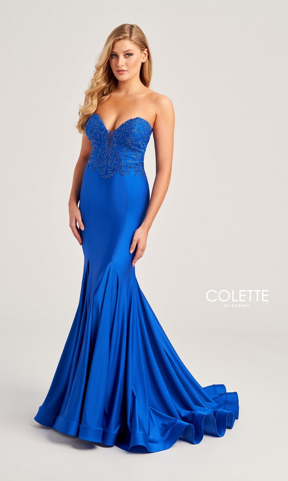 A woman wears the Colette Strapless Long Mermaid Prom Dress CL5112—a royal blue, floor-length gown with a fitted bodice, flared mermaid skirt, and embroidered detailing on the top.